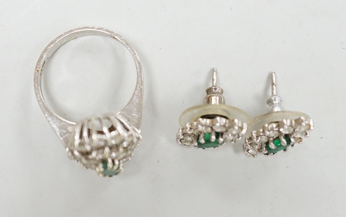 A modern 18ct white gold, emerald and diamond set oval cluster ring, size K/L and a pair of matching earrings, gross weight 7.2 grams.